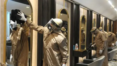 Getty Images A salon is disinfected by workers in PPE suits before reopening 2 June 2020 in Chandigarh