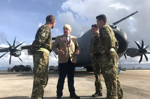 Georgina Stubbs/ PA Boris Johnson talks to pilots in front of an aircraft.