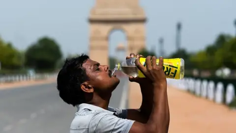 Getty Images A worker taking a break from cleaning weeds near India Gate in Delhi