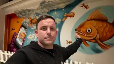 Nathan Murdoch Nathan Murdoch in front of his mural in Peterborough