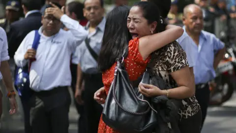 Clayton Conn Two women embrace as one cries on the street in Mexico City