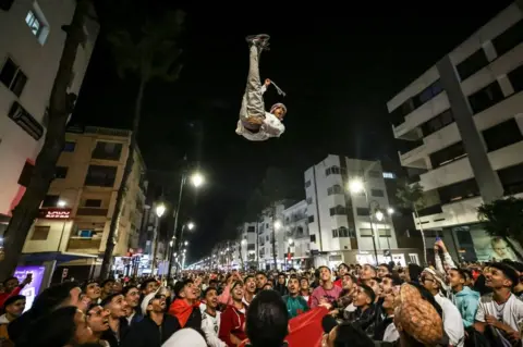AFP A crowd throw a man high into the air during celebrations.