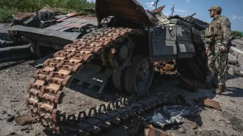 Reuters Ukrainian soldier examining wreckage of tank, near the village of Robotyne, 25 August 2023