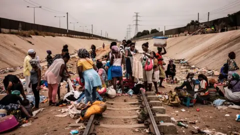 Getty Images Hawkers sell their products in an improvised market across a train track in the Viana district in Luanda