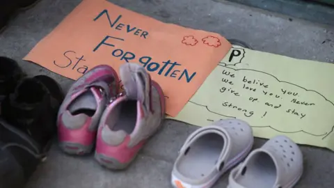 Getty Images Shoes, flowers, candles and signs are on the steps of the Metropolitan United Church. Indigenous youth are holding a sit in front of the Ryerson statue near Church and Gould on the Ryerson University campus.