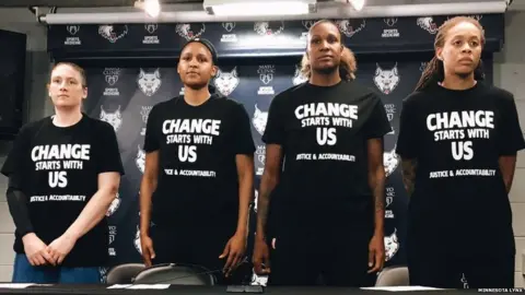 Minnesota Lynx Maya Moore, Seimone Augustus, Lindsay Whalen, and Rebekkah Brunson wearing black shirts with the phrase “Change Starts With Us: Justice & Accountability.”