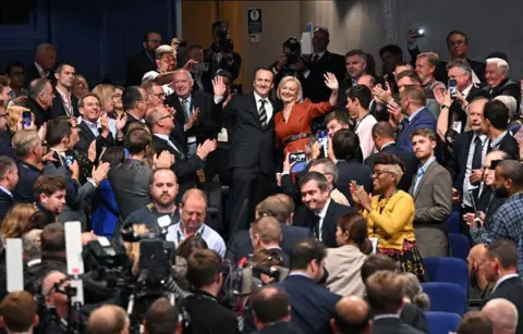 Oli Scarff/AFP Uk Prime Minister Liz Truss and her husband, Hugh O'Leary, wave to applauding delegates