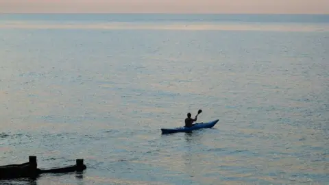 PA Media A man kayaks in the sea