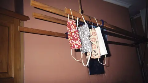 Chris Ruskin Three colourful face masks hang from an airing rack