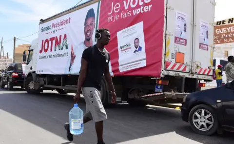 AFP A man walks past a truck with a poster of presidential candidate Ousmane Sonko on 3 February 2019, Dakar, Senegal
