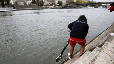 Reuters Employees of bicycle-sharing service Lime fish an abandoned electric scooter out of the River Seine in Paris, France