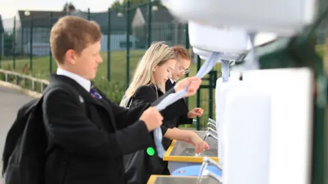 PA Media Pupils wash their hands at school