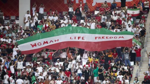 Getty Images Iranian fans hold up a banner reading 'woman, life, freedom' during the FIFA World Cup Qatar 2022 Group B match between England and Iran at Khalifa International Stadium on 21 November 2022 in Doha, Qatar