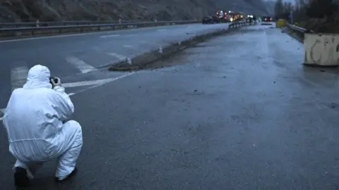 EPA An investigator takes a picture of the wreckage of a bus with North Macedonian plates that caught fire on a highway