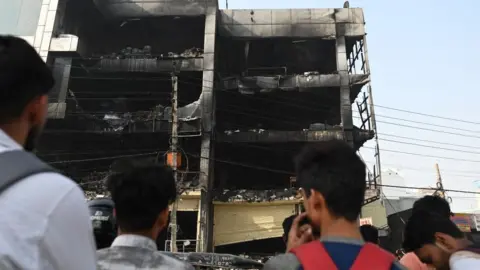 AFP/Getty Images Onlookers outside the burnt building in Delhi on 14 May