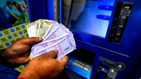 Getty Images man takes money out of cash machine