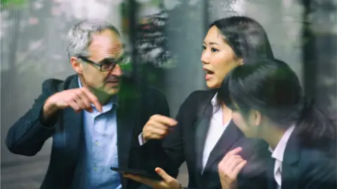 Getty Images man and two women in business meeting