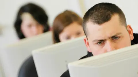 Alamy Three people looking at computer screens