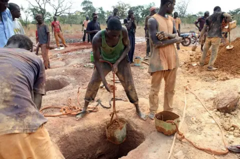 AFP Gold miners empty containers of earth removed from a mining shaft in Koflatie, Mali, on October 28, 2014, a mine located a few miles from the border with its southwestern neighbour Guinea.