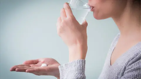 Science Photo Library Woman taking a pill