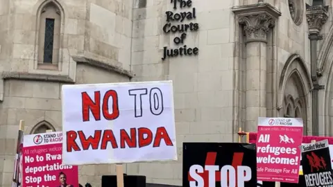 PA Media People seen holding placards to protest the Rwanda asylum policy outside the Royal Courts of Justice