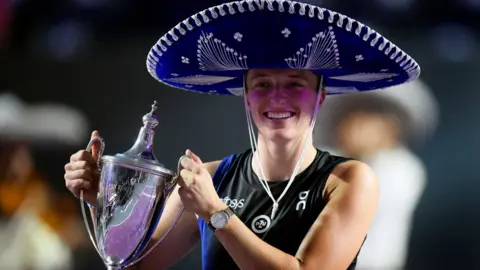 Iga Swiatek lifts the WTA finals trophy