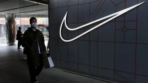 Getty Images A man walks past a store of the sporting goods retailer Nike Inc at a shopping complex in Beijing.