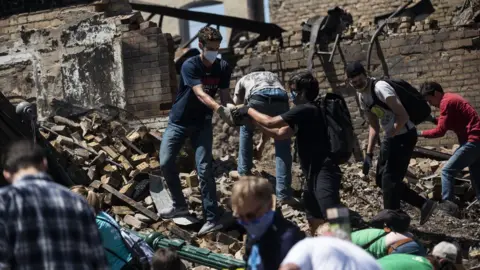 Getty Images People hand rubble to each other in the ruins of a burned building in Minneapolis