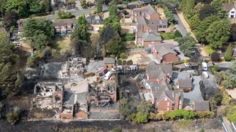 PA Media An aerial view of houses damaged by fire with a number of properties largely destroyed