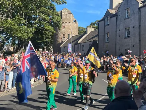 Group of competitors walking down the street with different colourful flags in hand