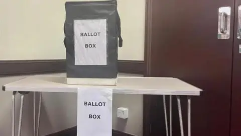 BBC A black ballot box labelled ballot box sits on a tale with the same label on it.