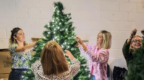 The Christmas Decorators Suffolk Four women decorating a Christmas tree with lights on it