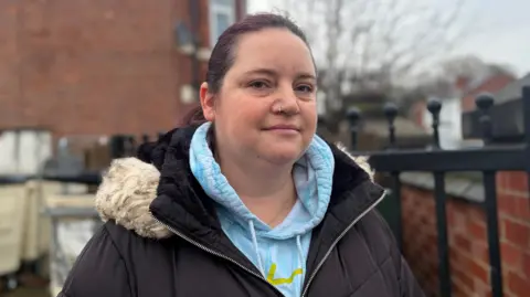 Woman wearing a black coat with light blue hoodie underneath.