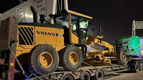 A big yellow machine. It is being towed. 