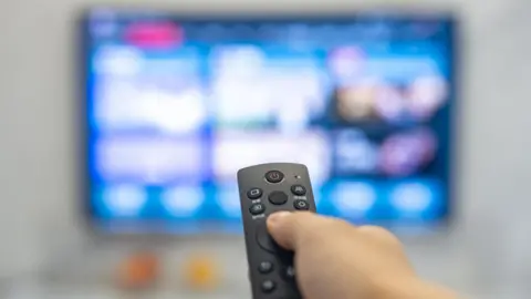 Getty Images A remote being pointed toward an out of focus tv screen.