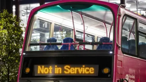 PA Media The top half of a pink double decker Translink bus with a sign that says: "Not in Service."