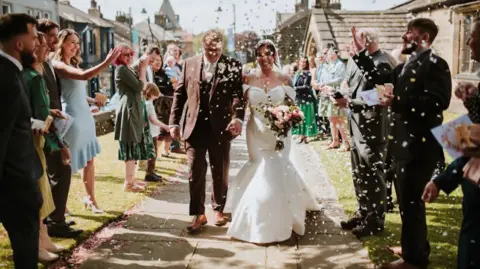That Wild Eye Photography A wedding photo of a couple who are walking out of a church as their guests throw confetti over them