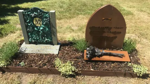 Kay Mason Billig Two graves can be seen in a raised plot, with engravings and a metal bouquet of flowers set in front of one of them.