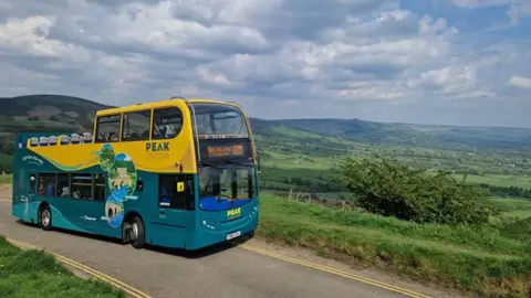 Tourism bus driving along a road with a hillside backdrop