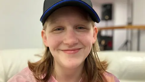 Young girl with baseball cap on smiling at the camera