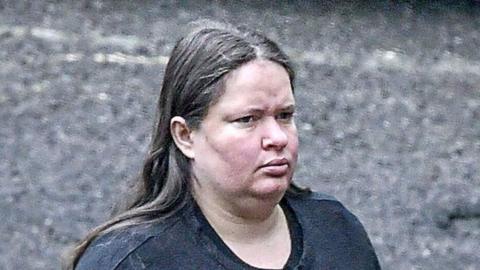 Jeniffer Rocha, a woman with long, straight hair who wears a dark top. She has a slight frown in this zoomed-in photograph taken at some distance outside court.