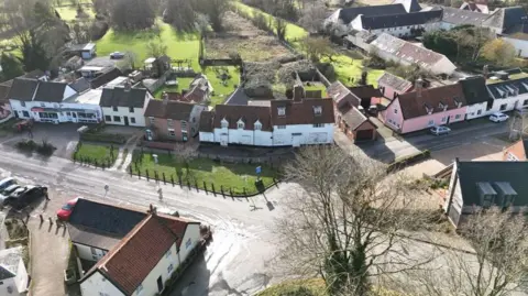 Shaun Whitmore/BBC An aerial view of the former King's Head pub, a white building, with terracotta-coloured roof tiles. It sits by a road, on a bend. There are green spaces at the front and rear of the line of buildings.