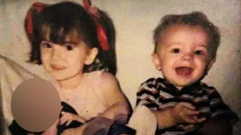 A young girl and boy, Meaghann and William Murphy when they were children, smiling at the camera.