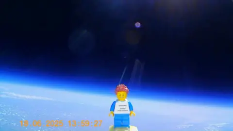 A lego figure is wearing a blue and white outfit and is floating in space