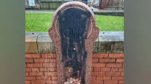 A memorial defaced by black paint