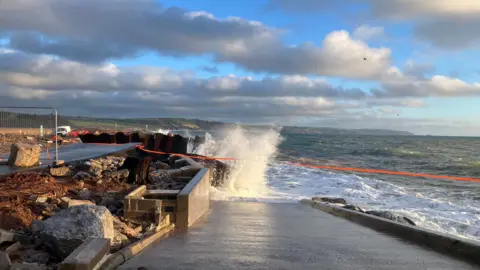 A wave crashes into the partially collapsed A379 Slapton Line between Torcross and Slapton.