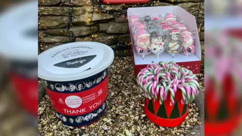 Richard Iles A donations box for Taxi Charity for Military Veterans featuring images of World War Two era servicemen and  women sits next two a box of candy canes and a box of lollipops in the shape of Father Christmas, snowmen and penguins. 