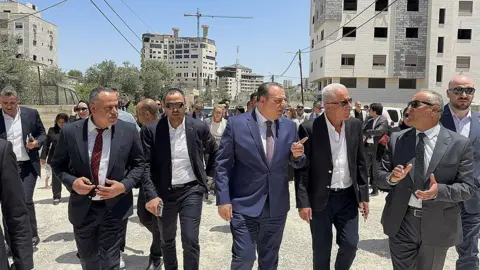 Foreign diplomatic delegation visits the Jenin refugee camp and conducts inspections. Men in suits and sunglasses are walking next to each other and talking.