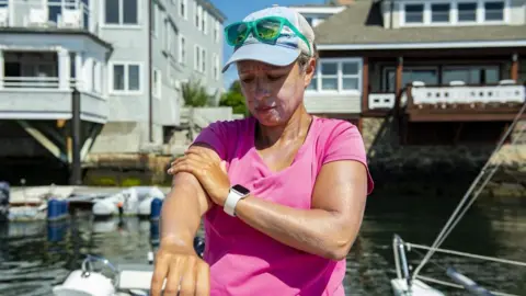 Anadolu via Getty Images A sailor puts on sunblock before heading out with her crew at the Helly Hansen Sailing World Regatta in Marblehead, Massachusetts on July 29, 2022.