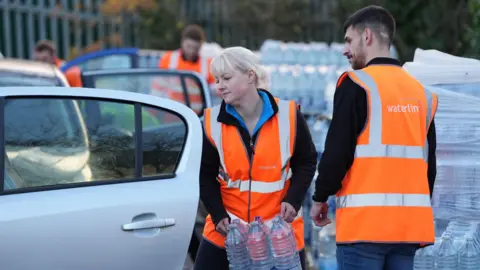 PA Media A worker hands out bottled water at the Tunbridge Wells Sports Centre after people in the area experienced a loss of water or low pressure since Saturday evening.